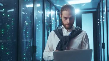 Adanmış ve odaklanmış bir profesyonel modern sunucu odası ortamında çalışırken bilgisayarı verimli bir şekilde yönetir.