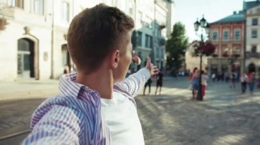 Genç adam, kamerayı tut ve şehrin etrafında gülümse. Sokakta konuş çocuk. Yavaş çekim yaşam tarzı, Kafkasyalı, neşeli çocuk, yavaş çekim moda öğrencisi.
