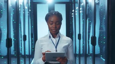 Yetenekli profesyonel bir kadın veri merkezinde, çeşitli sistemleri etkin bir şekilde yönetmek için bir tablet cihaz kullanıyor.