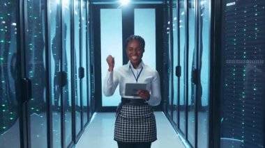 Profesyonel bir kadın birçok sunucu arasında tableti ile bir veri merkezinde ileri teknolojiyi yönetiyor.