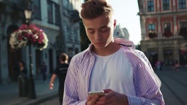 Yüzün gülsün genç adam. Sokağın ortasında dur. Telefonunu kullan. Kameraya bak, gülümse.