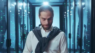 Düşünceli bir genç adam düşünceli bir şekilde fütüristik, teknolojik bir ortamda duruyor, gerçek yenilikleri somutlaştırıyor.