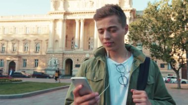 Gülümse yakışıklı genç adam. Telefonu kullan. Kulaklıkla müzik dinle. Etrafına bak.