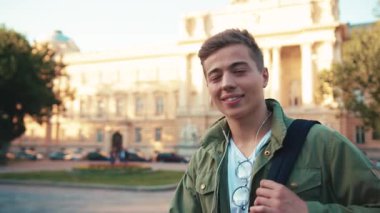 Kulaklık takan çekici bir genç adam sokak fotoğraflarına bakar yavaş çekimde günlük yaşam tarzını kapatır Kafkasyalı neşeli çocuk, yavaş çekimde moda öğrencisi