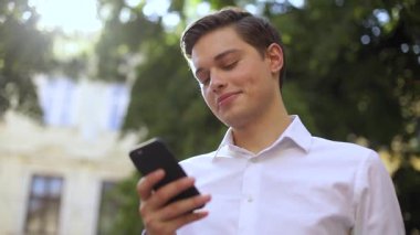 Aşağıdan çerçeve gülümseme başarılı iş adamı telefon kullanın şehir günbatımı bölge mobil şehir şehir şehir iş yöneticisi açık hava teknolojisi yakışıklı yürüyen cep telefonu dokunmatik ekranı