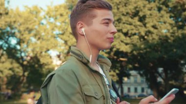 Yakışıklı genç adam, kulaklıkla telefon kullan. Etrafına bak. Steet City 'de gülümse.