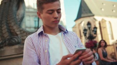 Elinde cep telefonu tutan portre çocuğu mutlu olmak için fotoğraf çekiyor. Şehir merkezinde sıradan, yakışıklı bir öğrenci caddesinde, internet iletişimi, akıllı telefon teknolojisi cep telefonu ağının dışında duruyor.