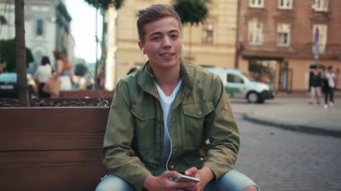 Yakışıklı genç adam, telefon kullan. Kulaklıkla müzik dinle. Etrafına bak ve gülümse.