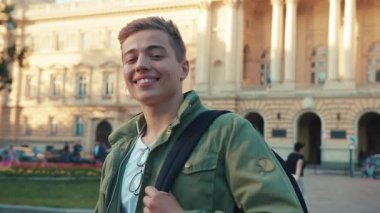 Kulaklık takan genç adam kameraya bak. Gülümse. Sokakta mutlu ol. Yavaş çekim yaşam tarzını kapat.