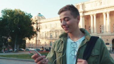 Yakışıklı genç adam cep telefonuyla konuşuyor. Kulaklıkla konuşuyor. Etrafına bak. Sokakta yürüyorsun.