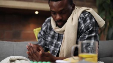 Gri koltukta oturan ekose gömlek ve bej eşarp giyen Afrikalı sempatik bir adam. İlaçlardan bahseden hasta, yakışıklı bir gencin portresi. Yüksek sıcaklık.