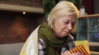 Güzel, hasta, battaniye giyip öksüren, buz gibi soğuk bir büyükanne. Hap konuşan mutsuz bir kadın. İçeride. Yakın plan. Boğaz ağrısı. Yüksek ateş. Hastalık..