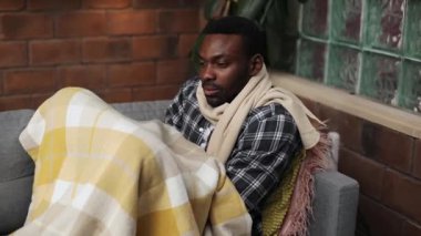 Oturma odasındaki kanepede yatan Afrikalı hasta. Hasta, yakışıklı bir öğrencinin burun silme portresi. Hastalık. Kapalı.