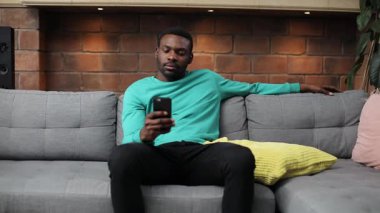 Sakallı, naneli süveter ve siyah pantolon giyen çekici Afrikalı genç adam portresi. Midesinde keskin bir ağrı olan iyi bir adam. Kapalı.