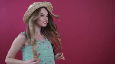 Dalgalı saçları olan güzel genç bir kadın, fırlatılmış çiçeği yakalar, mutlu bir şekilde gülümser, renkli arka planda kameraya poz verirken sevimli bir şekilde kokar. Şık kıyafetler, doğal güzellik. Hayatın neşesi, mutlu hissetmek. Kadın portresi