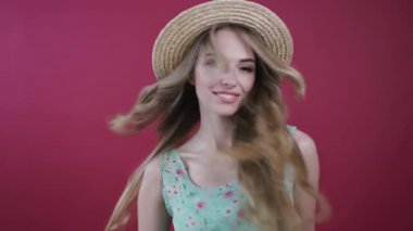 Güzel, uzun saçlı, şık yaz kıyafetleri içinde mutlu bir sarışın kadın havada asılı duruyor, fırlatılan çiçeği yakalıyor, aromasının tadını çıkarıyor ve kameraya hoş bir şekilde gülümsüyor. Romantik atmosfer, aşık olmak, çıkmak. Kadın portresi, renkli arkaplan