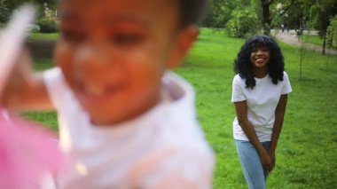 Güzel Afrikalı genç bir kadın güzel kızına hava öpücüğü yolluyor. Yakışıklı genç adam, gülümseyen utangaç çocuğu elinde tutuyor. Yakın plan. Açık havada. Yaz zamanı..