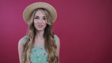 Son derece çekici genç sarışın kadın kameraya döner, baştan çıkarıcı bir şekilde saçlarını parmağında döndürür ve renkli arka planda kameraya poz verirken sevimli bir şekilde gülümser. Flört, pozitif ruh hali. Kadın portresi