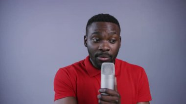 Çekici Afro-Amerikalı adam mikrofon kullanıyor ve gri arka planda vaaz veriyor. Erkek portresi, yakın görünüm