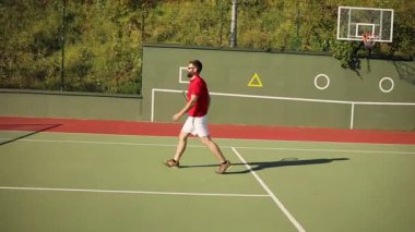 Sporcu sakallı adam topu almak için tenis sahasına doğru yürür. Eğitim, hobi, profesyonel oyuncular değil. Eğleniyorum, hafta sonu rahatlıyorum. Erkek portresi