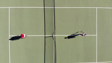 Bir kadın ve erkeğin tenis maçını tartışmak için internetin yanında buluşup kimin önce atış yapacağına karar verirken, taş, kağıt, makas oynarken yüksek açılı çekim. Tenis, eğlenmek, hafta sonu.