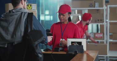 Modern dağıtım dairesinde çalışan kırmızı üniformalı iki çok ırklı kurye müşterilere iş birliği yapıyor. Postanedeki Pilite personeli.