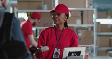 Postanede müşterilere hizmet veren çok ırklı bir çift işçi. Afro-Amerikalı güzel bir kadın dağıtım departmanında kameraya gülümsüyor. Meslek kavramı.