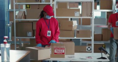 Posta Ofisinde Maskeli Genç İşçilerin Çoklu Etnik Çifti Pandemik Coronavirus Karantinası 'nda İletişim ve Paketleme Kutuları Giyiyor.