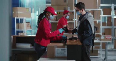 Pandemik postanede, çok ırklı tıbbi maskeli personelin karantina sırasında paket teslimatı için beyaz müşteri siparişi vermeleri bekleniyor..