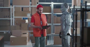 Bilgisayar tableti kullanan beyaz erkek çalışan yapay zeka teknolojisi sibernetik robot posta dağıtım atölyesinde işbirliği yapıyor..