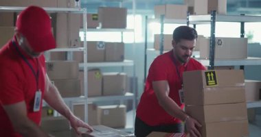 Postane takım kaptanı. Kooperatif kırmızı üniformalı birkaç sakallı işçi gelecek teslimatlar için karton kutuları taşıyıp ayırıyor..