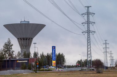 Oulu, Finlandiya - 30 Kasım 2024: Bulutlu bir sonbahar gününde şehir manzarası. Maikkula su kulesi. Yüksek voltaj güç hattı