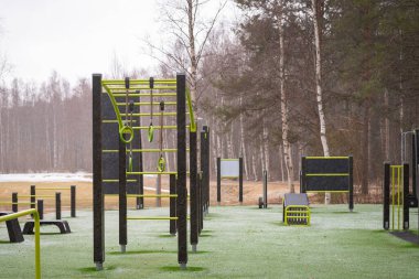 Açık hava spor salonu. Spor simülatörleri. Spor aletleri. Spor için ağırlık antrenman ekipmanlarıyla şehir dışı spor sahası. Spor ve dinlenme alanı. Sokak çalışması. Aniden kar yağdı..