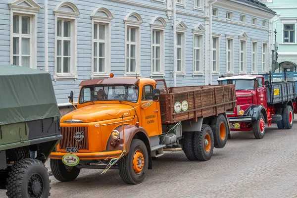 Şehir caddesi boyunca turuncu Volvo kamyonlar sürüyor. Geleneksel klasik eski araba şehir gezisi. Oulu, Finlandiya - 1 Mayıs 2025