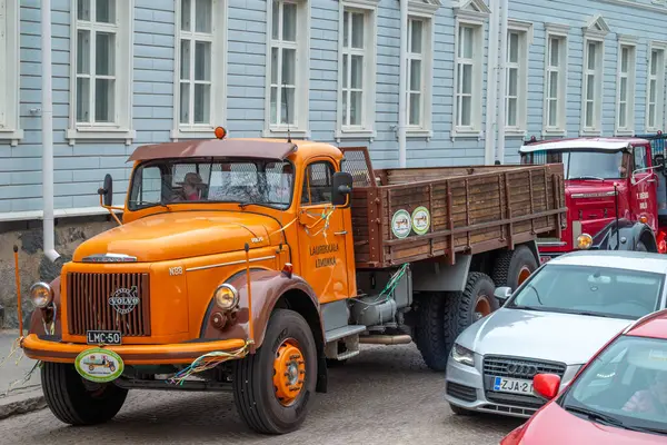 Şehir caddesi boyunca turuncu Volvo kamyonlar sürüyor. Geleneksel klasik eski araba şehir gezisi. Oulu, Finlandiya - 1 Mayıs 2025