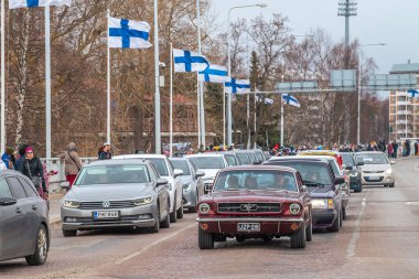 Retro araba Ford. Fin bayrakları arka planda görünür. Geleneksel klasik eski araba şehir gezisi. Oulu, Finlandiya - 1 Mayıs 2025