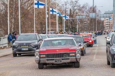 Retro araba. Fin bayrakları arka planda görünür. Geleneksel klasik eski araba şehir gezisi. Oulu, Finlandiya - 1 Mayıs 2025