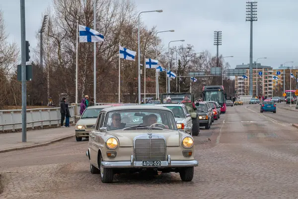Retro araba Mercedes. Fin bayrakları arka planda görünür. Geleneksel klasik eski araba şehir gezisi. Oulu, Finlandiya - 1 Mayıs 2025