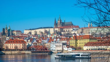 Modern Electric Prag Boat tur gemisi, tarihi nehir kıyısı binalarıyla Vltava Nehri 'nde yol alıyor. Prag, Çek Cumhuriyeti - 18 Şubat 2025.