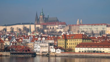 Vltava Nehri 'nin karşısındaki görkemli Prag Kalesi kompleksi ve Küçük Şehir çatılarının panoramik manzarası tarihi Avrupa şehir manzarasını gözler önüne seriyor. Prag, Çek Cumhuriyeti - 24 Şubat 2025.