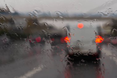 Islak bardağa yansıyan arabanın farları. Su damlalı ıslak bardak. Otoyolda sağanak yağmur.