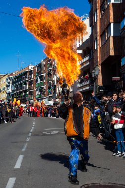 Madrid, Spain- January 21, 2023: Parade to celebrate the Chinese New Year through the streets of Madrid. Bonfire man releases fire from the mouth at the new year parade.