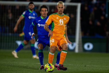 Madrid, Spain- January 28, 2023: Soccer match between Real Betis balonpie and Getafe F.C in Madrid. The Betis player Sergio Canales fights with an opponent for the ball.