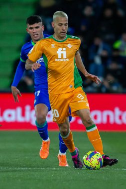 Madrid, Spain- January 28, 2023: Soccer match between Real Betis balonpie and Getafe F.C in Madrid. The Betis player Sergio Canales fights with an opponent for the ball.
