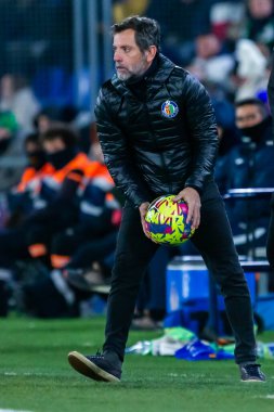 Madrid, Spain- January 28, 2023: Soccer match between Real Betis balonpie and Getafe F.C in Madrid. The coach of Getafe F.C,  Sanchez Flores in the band with the ball. clipart