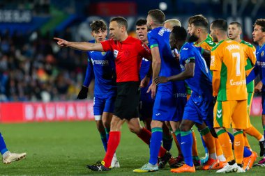 Madrid, Spain- January 28, 2023: Soccer match between Real Betis balonpie and Getafe F.C in Madrid. Match referee signals penalty during the match. The players complain to the referee.