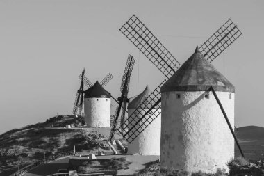 Mills, Consuegra kasabasında. Tepedeki birkaç beyaz yel değirmeni ve kahverengi yel değirmeninin manzarası. Antik mimari. Çiftlik evleri.