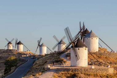 Mills, Consuegra kasabasında. Tepedeki birkaç beyaz yel değirmeni ve kahverengi yel değirmeninin manzarası. Antik mimari. Çiftlik evleri.