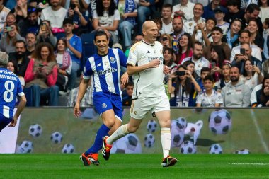 Madrid, Spain- March 23, 2024: Solidarity match between Real Madrid Leyendaa and Porto Vintage at the Santiago Bernabeu. Zidane returns to Real Madrid. Zidane dresses in white. Ziz with the ball clipart