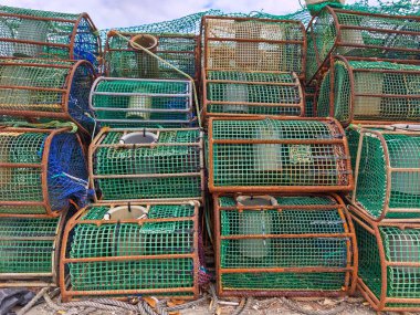 Ribadeo, İspanya - 13 Ağustos 2025: balıkçılık ekipmanları ve teçhizatı. Balık ağları ve toplar. Kabuklu deniz hayvanı kafesleri. Ribadeo limanına demir atmış bir balıkçı teknesi..